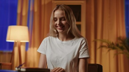 A smiling girl blonde student rubs hands contentedly, rejoices at passing exam perfectly. A pretty young lady in bliss and emotionally filled after a successful date, acceptance to the desired job or