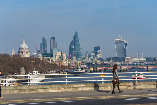 London, UK - March 13th 2014: A woman walking across Waterloo Bridge. In the background is the River Thames, St. Paul's Cathedral, Gherkin and Walkie Talkie.