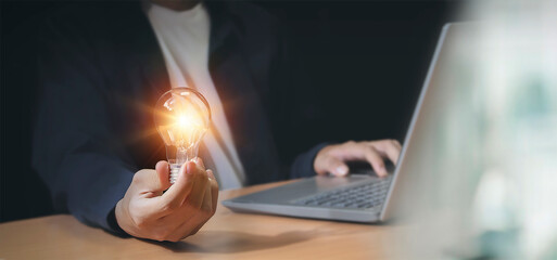 businessman holding an innovative light bulb creating new ideas inspirational ideas and problem solving