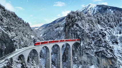 Fotobehang Snow falling and Train passing through famous mountain in Filisur, Switzerland. Train express in Swiss Alps snow winter scenery. © tawatchai1990