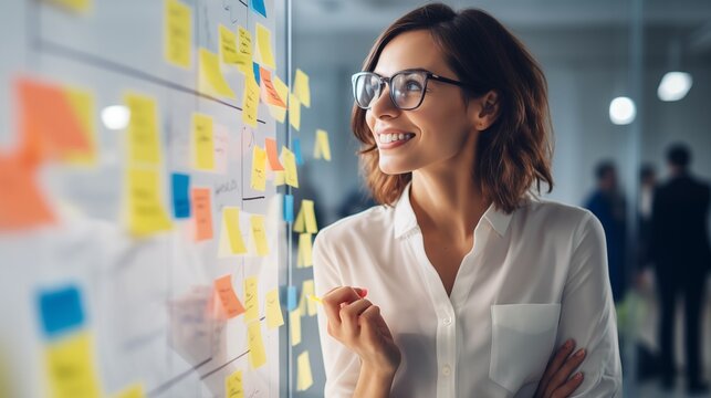 Businesswoman reads information on a notepad attached to a whiteboard with keen interest, showcasing her focused and attentive approach to information processing.