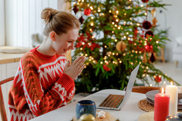 young blonde woman sits at table in kitchen with Christmas tree, gets unexpected great news, feels elation and thrilled. unbelievable and astonishing information