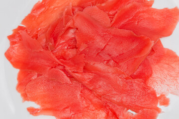 Red pickled slices of ginger on white dish, close-up
