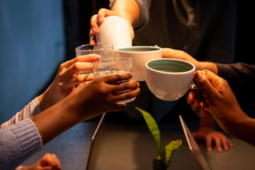 The image captures an intimate moment of a communal tea serving. Hands of diverse descent are seen...