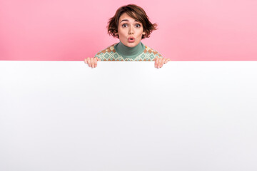 Photo promoting empty space banner young girl hold paper placard offer pouted lips speechless crazy deal isolated on pink color background