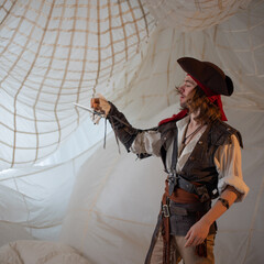 A cheerful and funny pirate in a cocked hat, a guy in a pirate costume with a gun, a sea robber, a...