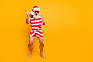 Full length photo of cheerful funny guy wear new year swimsuit hat sunglass enjoying disco empty space isolated yellow color background