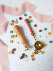 Vintage wooden wax seal stamp and colorful wax bead on a white background.