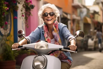 Gordijnen Happy mature woman driving scooter in street © Olga