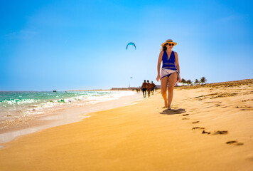 Beautiful woman walking on sunny beach Santa Maria, Sal Island, Cape Verde
