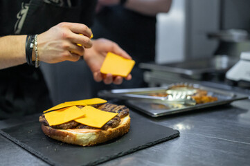 chef hand cooking big large cheese burger on restaurant kitchen