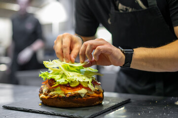 chef hand cooking big large cheese burger on restaurant kitchen