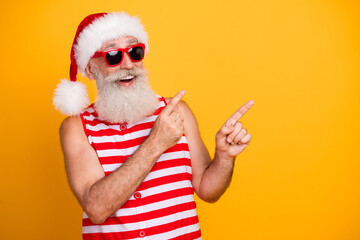 Photo of impressed funky senior guy dressed christmas swimwear hat pointing two fingers empty space...