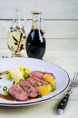 Roast duck fillet with mashed potato and orange sauce on wooden background