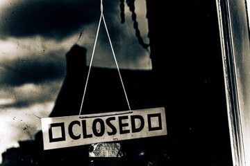 closed sign hung on dark abandoned building