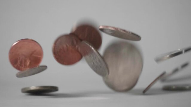 Coins falling onto a white surface.