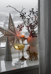 Cozy winter Christmas evening - a glass of white wine, Christmas decor, a lighted candle on the...