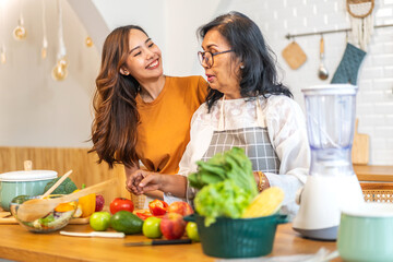 Portrait of happy love asian family senior mature mother and young daughter smiling cooking vegan food healthy eat with fresh vegetable salad and fruit in kitchen, care, insurance, elderly health care