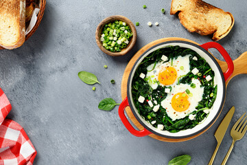 Green shakshuka with fresh spinach, fried eggs and feta cheese cubes, healthy breakfast. top view - 687157812