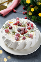 Pavlova meringue cake decorated with frozen cranberry and rosemary. Cake for christmas event.