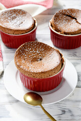 Freshly baked chocolate souffle with powdered sugar, french dessert. white wooden background