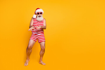 Full length photo of good mood senior guy christmas swimwear hat having fun discotheque empty space...