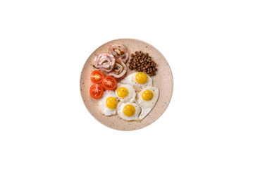 Delicious nutritious breakfast of fried quail eggs, bacon, legumes and cherry tomatoes