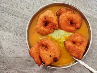 Homemade mendu vada sambhar with chutney in plate on kitchen tile floor, copy space