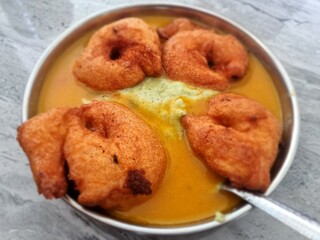 Homemade mendu vada sambhar with chutney in plate on kitchen tile floor, copy space