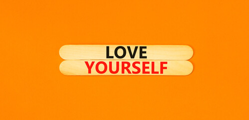 Love yourself symbol. Concept words Love yourself on beautiful wooden stick. Beautiful orange table orange background. Psychology love yourself concept. Copy space.
