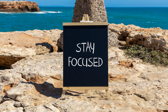 Stay focused symbol. Concept words Stay focused on beautiful black chalk blackboard on a beautiful beach stone background. Business, support, motivation, psychological stay focused concept. Copy space