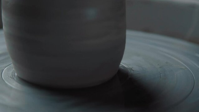 The potter works with the product and cuts off the extra clay using the string tool, close-up, without people. Hands of a potter, concept of handwork, creativity.