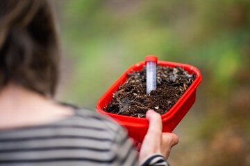 farmer collecting soil samples in a test tube in a field. Agronomist checking soil carbon and plant...