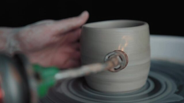 Potter works: firing clay on a potter's wheel. Close-up, only hands in the frame. Ceramist preform made of clay jars and makes roasting using the burner.