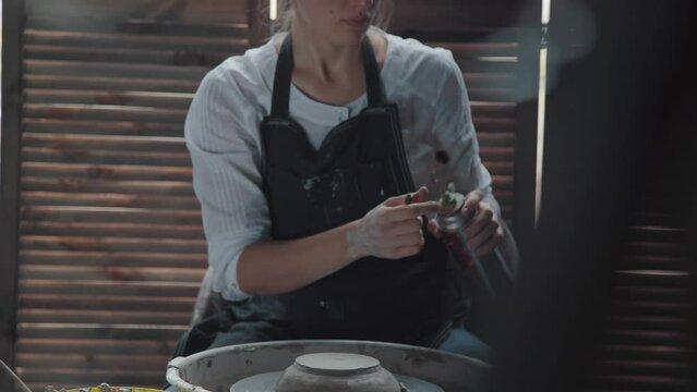 Woman potter in an apron with clay stains lights the gas burner. She wants to burn the product of clay. Creative pottery workshop. General plan