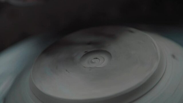 Potter works using the tool and removes excess clay, makes a pattern on the product. Close-up. Only the hands and the product, the natural process of work.