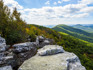 Fototapeta na wymiar The beautiful wilderness with wooded mountains and early fall cclors with rocks in the foreground as seen from Big Schloss via Wolf Gap Trail on the border between West Virginia and Virginia.