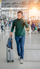 An Asian young  man wearing green color wool sweater and taling on smart phone at the  airport...