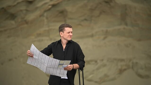 man in the desert. a man holds a paper map in his hands. man looking at a paper map.High-quality shooting in 4K