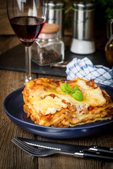 Piece of tasty hot lasagna with red wine.