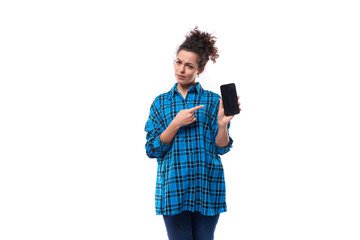 a european young lady with a curly ponytail hairstyle dressed in a blue shirt uses a smartphone....