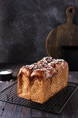 Butter brioche bread sprinkled with pearl sugar on black grille on a dark wooden background.  Wheat bread recipes.