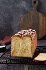 Butter brioche bread sprinkled with pearl sugar on black grille on a dark wooden background.  Wheat bread recipes.