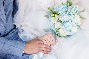 Newlyweds' hands with wedding rings and wedding bouquet