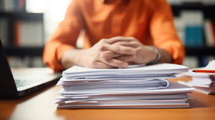Close-up of a man working with a stack of documents and reports on his office desk