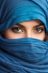 Close-up portrait of a beautiful Arab Muslim woman wearing a blue hijab. Only the eyes and direct gaze into the camera are visible.
