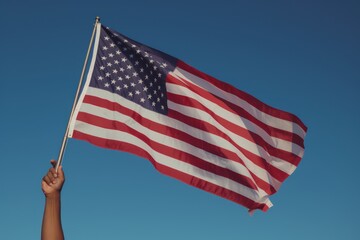 Hand holding American flag on blue sky background. AI generated