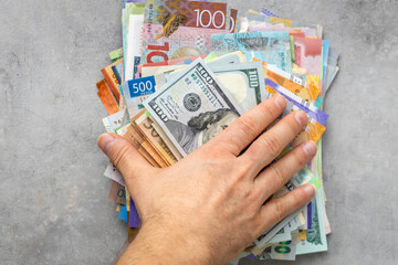 hand placed on a pile of money from all over the world. Financial concept, currency markets, money...