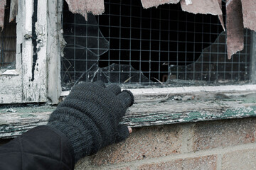 Concept of a would-be thief wearing knitted gloves about to enter an abandoned building on an...