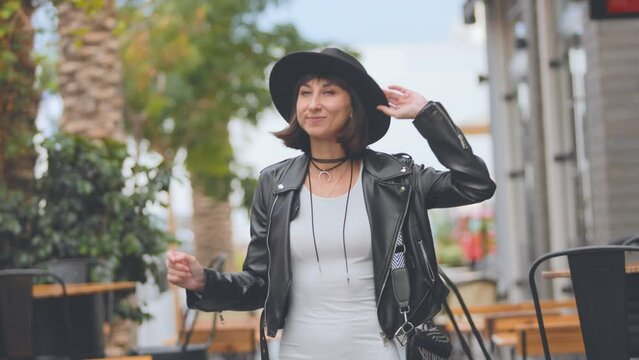 Fashionable woman in a black stylish leather jacket and dress dances on the street. urban fashion and style.
